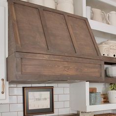 a kitchen with white tile and wooden cabinetry above the stove top, is seen in this image