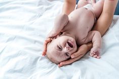 a woman holding a baby on top of a bed