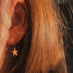 a close up of a person's ear with a star earrings on top of it