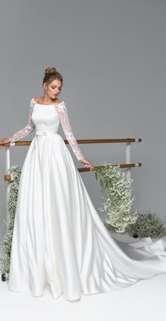 a woman in a white wedding dress standing on a rail with her hands on her hips