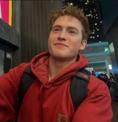 a man in a red hoodie taking a selfie