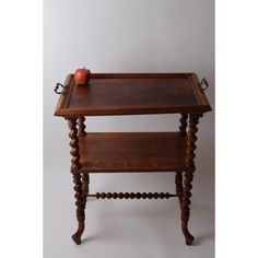 an apple is sitting on top of a small wooden table with two legs and a tray