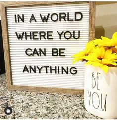 a sign that says in a world where you can be anything, with yellow flowers