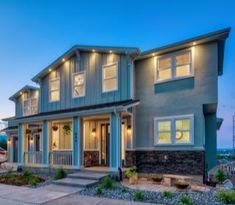 a large house with many windows and lights on it's front porch at dusk