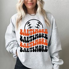 "Baltimore Baseball Sweatshirt, Baltimore Baseball shirt, Vintage Style Baltimore Baseball Sweatshirt, Baltimore Baseball Fan Gift  -Please check Color and Size Charts before placing the order. You can find them in the listing's photos (Depending on what device you are viewing this listing colors may vary slightly). -Returns and exchanges are accepted only if there are defects \"No Extra Costs\" We create custom t-shirts with great designs for everyone's liking. If you don't find the size or color you would like, please message us and we will be happy to  accommodate! Baltimore Baseball Sweatshirt, Baltimore Baseball shirt, Vintage Style Baltimore Baseball Sweatshirt, Baltimore Baseball Fan Gift  PRODUCT Sweatshirt :   Gildan 18000 -  Medium-heavy fabric (8.0 oz/yd² (271.25 g/m -   Loose f Long Sleeve Tops For Baseball Season, Fall Graphic Print Tops For Sports Events, Graphic Print Tops For Fall Sports Events, Graphic Print Tops For Sports Events In Fall, Team Spirit Graphic Print Tops For Fall, Team Name Long Sleeve T-shirt For Baseball Season, Long Sleeve T-shirt For Baseball Season Game Day, School Spirit Graphic Sweatshirt For Baseball Season, School Spirit Graphic Print Sweatshirt For Baseball Season