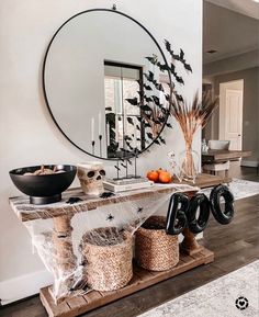 a table with halloween decorations on it in front of a large mirror and black bowl