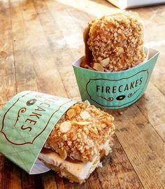 two donuts sitting on top of a wooden table next to a cup filled with ice cream