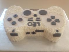 a cake shaped like a video game controller on top of a white tablecloth covered in frosting