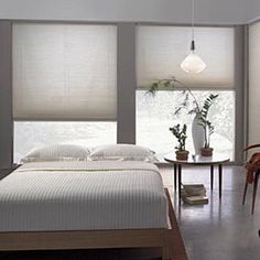 a bed sitting in a bedroom next to a window with blinds on the windowsill