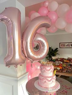 a pink birthday cake and balloons in the shape of the number six on a table