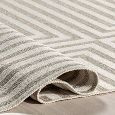 a close up view of a rug on the floor with white and grey striped fabric