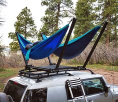 a car with two hammocks on top of it's roof in the woods