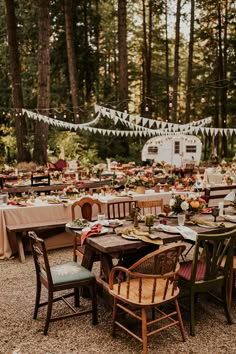 an outdoor dining area with tables and chairs set up for a party in the woods