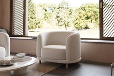 a living room with two white chairs and a coffee table in front of a window