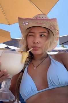 a woman wearing a straw hat drinking a drink