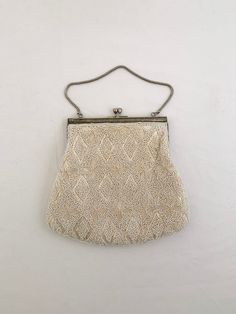 "This is a pretty hand beaded evening bag by Du-Val, Hand Made in Hong Kong. Both sides of the bag have the same geometrical decoration with shiny pearl-like white and tubular beads.  The purse is lined in a soft off white satin fabric with a small pocket and the original tag (interior does have some staining). The tops of the kiss clasp closure are topped with aurora borealis rhinestones.  The frame is in a silver tone metal but missing its decorative panel on one side.  The short silver handle White Satin Fabric, Bride Bag, Prom Accessories, Beaded Evening Bags, Cruise Wear, Pretty Hands, Evening Purse, Beaded Clutch, The Kiss