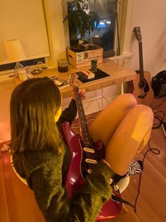 a woman sitting on top of a red chair holding a guitar in front of her