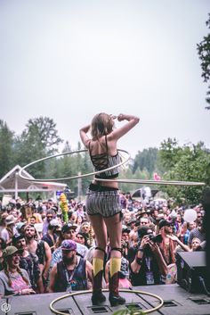 a woman standing on top of a stage holding a hula hoop in front of a crowd