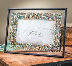 a frame made out of beads and glass on top of a wooden table next to a box