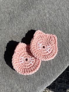 two pink crocheted buttons sitting on top of a gray blanket