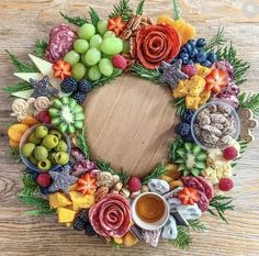 an arrangement of fruits and vegetables arranged in a wreath on a wooden table with a cup of coffee