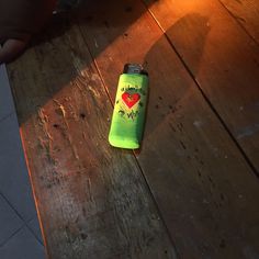 a green can sitting on top of a wooden floor next to a person's leg