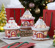 gingerbread houses decorated with icing and candy on a table in front of a christmas tree