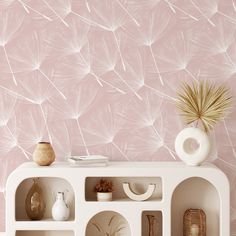 a white shelf with vases and other items on it in front of a pink wall