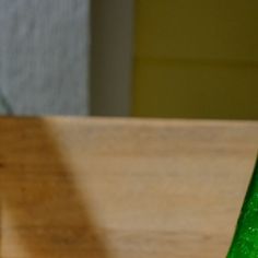 a green glass bottle sitting on top of a wooden table