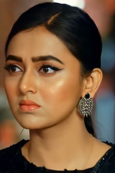 a woman with dark hair wearing earrings