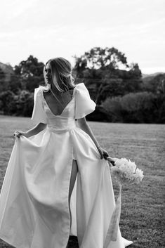 a woman in a white dress walking through a field