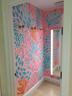 an open door leading to a bathroom with pink and blue wallpaper