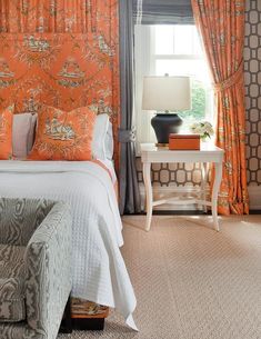 a bedroom with an orange wallpaper and white bed in front of a large window