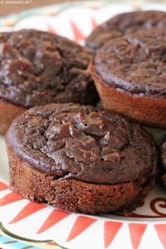 three chocolate muffins on a plate sitting on a table