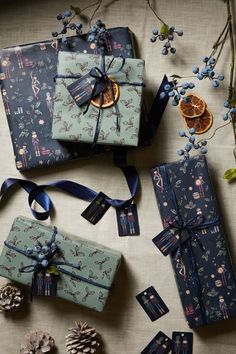 presents wrapped in blue paper and tied with ribbons, surrounded by pine cones and oranges