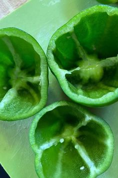 three green peppers cut in half on a cutting board