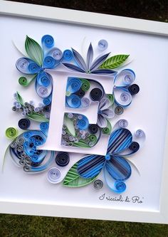 the letter e is surrounded by blue and green paper flowers, leaves and swirls