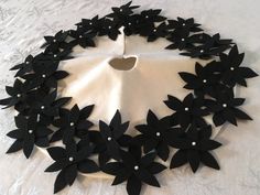 a white cloth with black flowers and pearls in the center, on top of a table