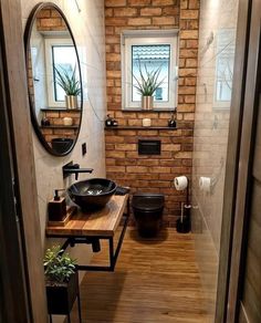 a bathroom with a sink, mirror and toilet inside of it next to a brick wall