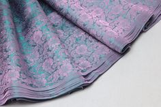 purple and teal brocaded silk fabric on white tablecloth with grey background