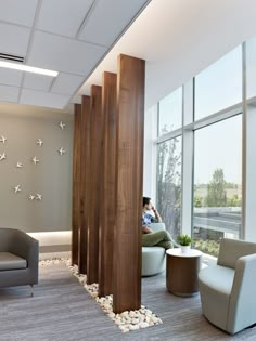 a man sitting on a chair in an office with birds flying around the room wall