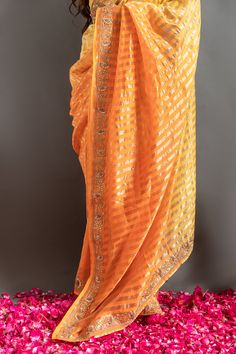 Yellow and orange saree with an ombre woven stripe base highlighted by zardozi embroidery. Comes with matching embroidered blouse.
Components: 2
Pattern: Embroidered
Type Of Work: Zardozi, Gotapatti
Neckline: Round
Sleeve Type: Half
Fabric: Tissue
Color: Orange,Yellow
Other Details: 
Woven zari stripes
Placed embroidery
Occasion: Mehendi and Haldi,Sangeet - Aza Fashions Orange Pre-draped Saree For Diwali, Traditional Orange Georgette Pre-draped Saree, Orange Georgette Blouse Piece For Puja, Orange Bollywood Pre-draped Saree With Zari Work, Festive Orange Pre-draped Saree, Navratri Orange Choli With Cutdana, Navratri Orange Cutdana Choli, Traditional Orange Banarasi Silk Pre-draped Saree, Orange Georgette Blouse Piece With Dupatta