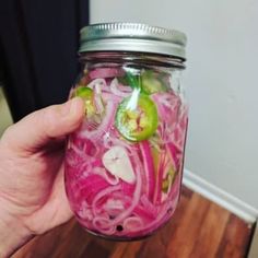 a person holding a jar filled with pickles and onions