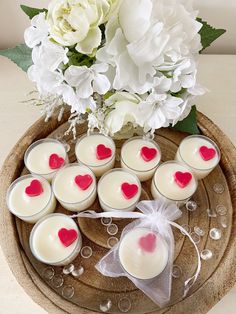 small candles with hearts on them are sitting on a wooden tray next to white flowers