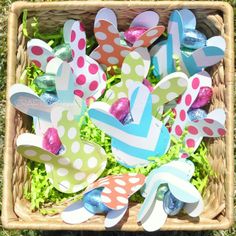 an easter basket filled with colorfully painted eggs and paper flowers in it's center