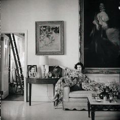 black and white photograph of a woman sitting on a couch in front of a painting