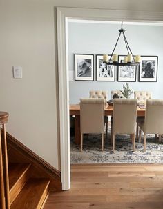 a dining room table with chairs and pictures on the wall above it, along with stairs