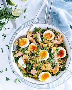 a white bowl filled with rice and eggs on top of a table next to utensils