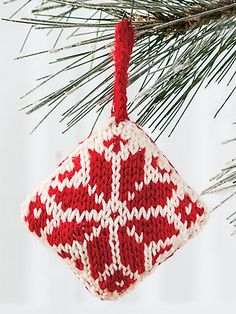 a red and white ornament hanging from a pine tree's needled needles