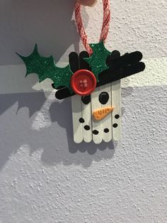 a christmas decoration made out of pops sticks and glue on top of a white wall